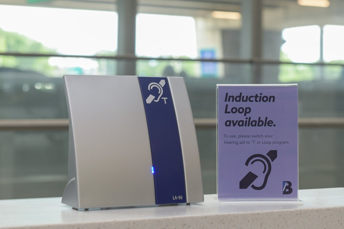 Photograph of an Induction Loop device and sign at LaGuardia airport.