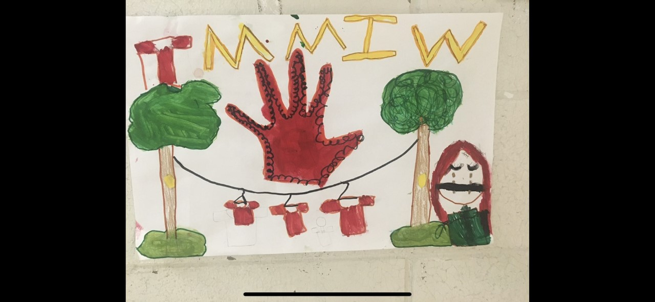 Milee's art says: TMMIW, and has red shirts hanging on a clothesline, and a woman crying in the foreground