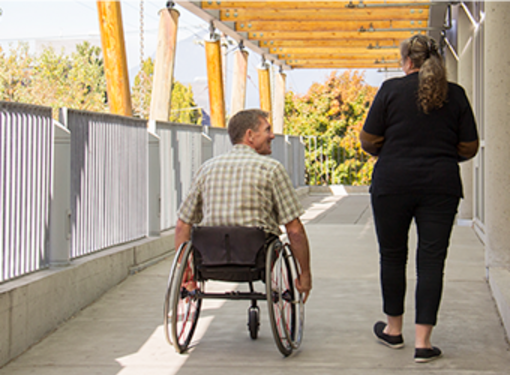 Two people, one person using a wheelchair, travelling up a ramp