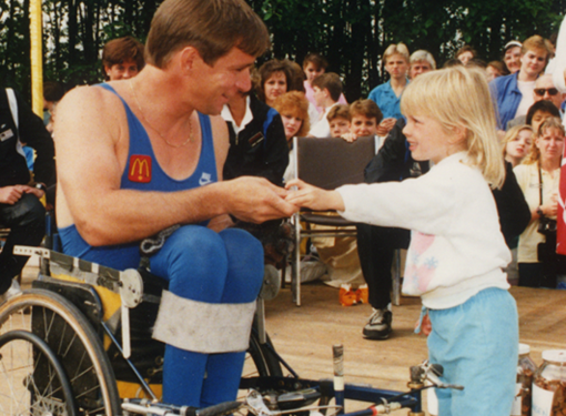 A little girl gives Rick Hansen a donation at a McDonald's restaurant during the Man in Motion World Tour
