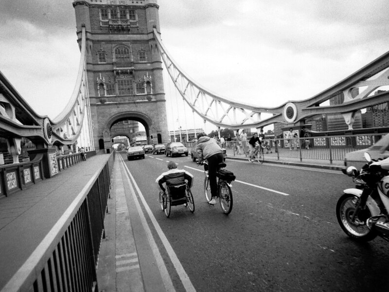 Rick Hansen wheeling over Tower Bridge, accompanied by Amanda Reid on bicycle.