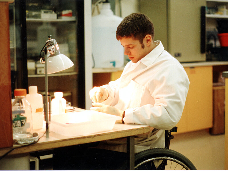 Un homme en fauteuil roulant effectue des tests dans un laboratoire.	