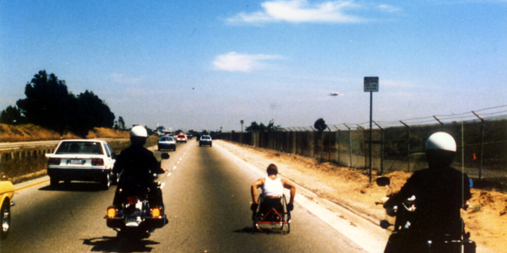 Rick Hansen with a police escort while wheeling in Florida in 1985.