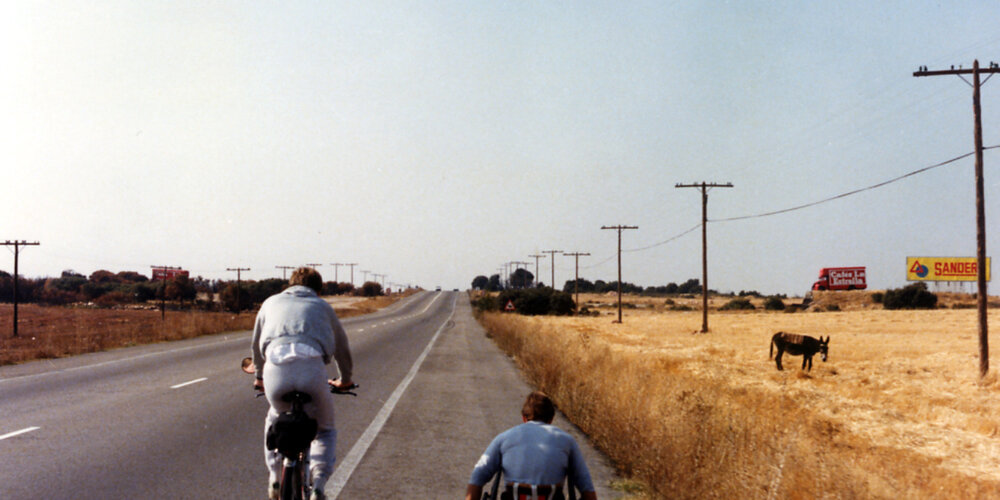 Rick Hansen wheeling through the Spanish countryside, accompanied by Amanda Reid on bicycle.