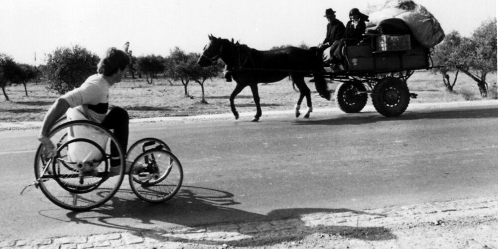Rick Hansen wheels past locals in a horse and buggy in rural Portugal during early November of 1985. 