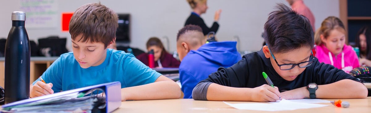 children in classroom taking notes on their desk