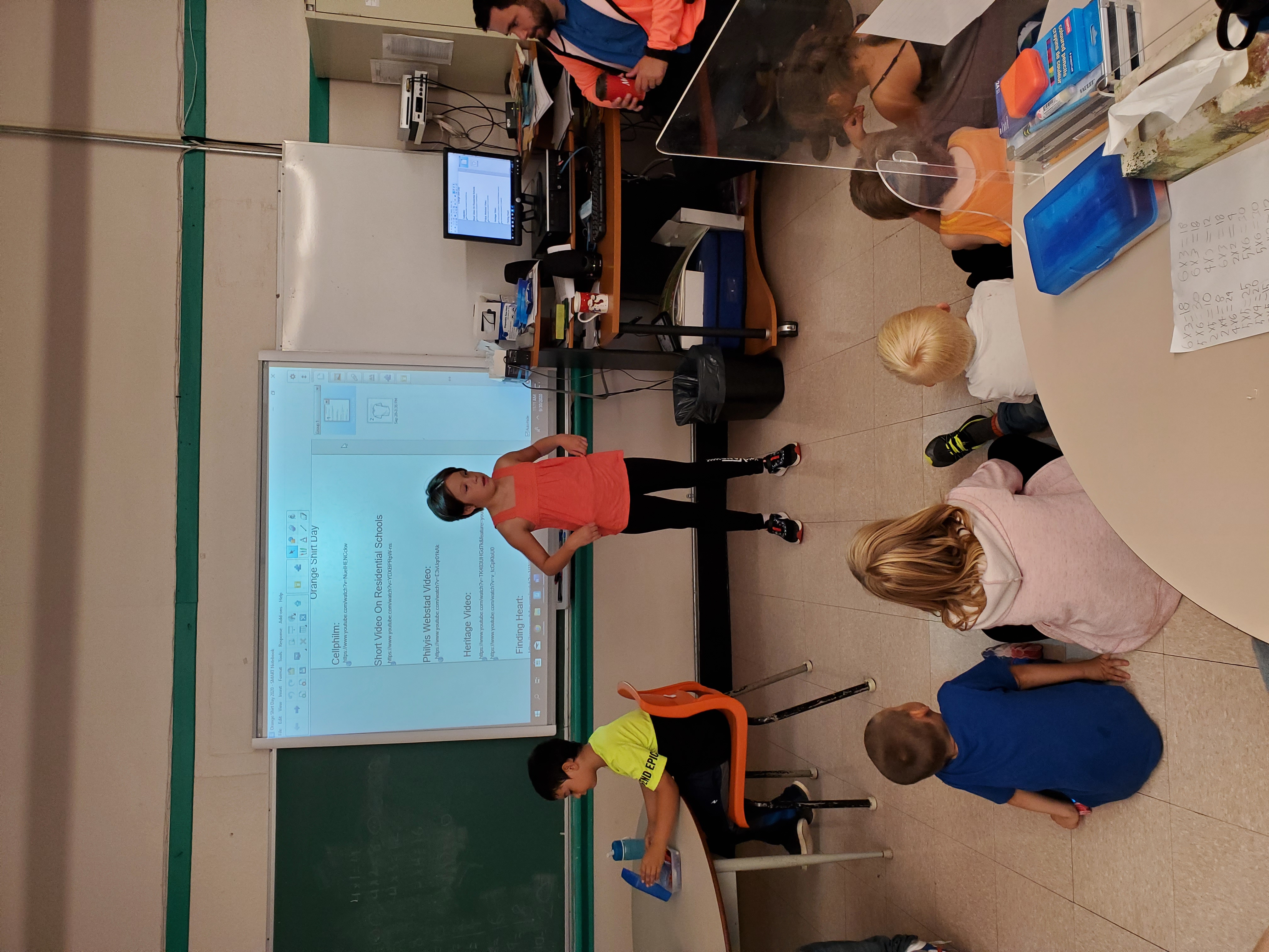 young girl at the front of a classroom presenting