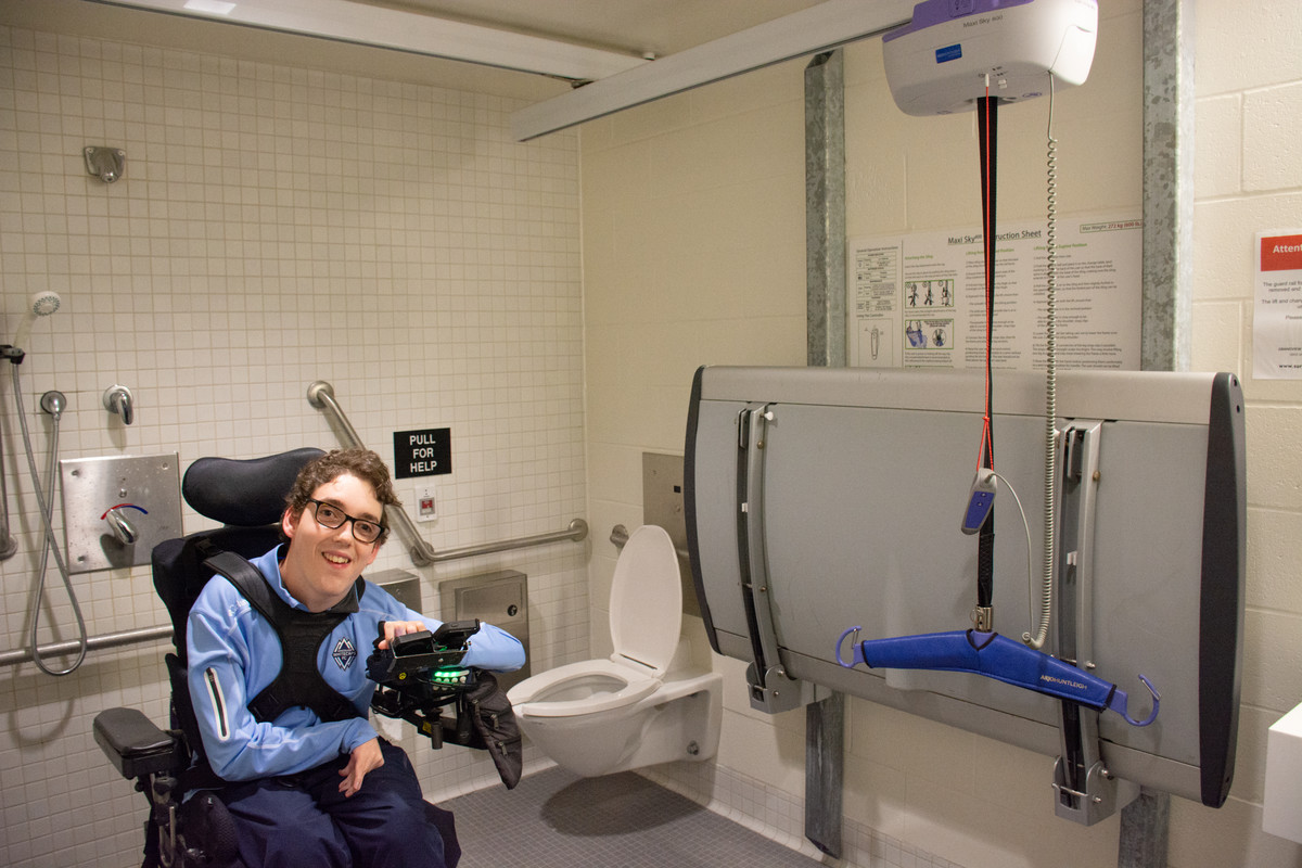 Nathan in power wheelchair in universal change room at the Grandview Heights Aquatic centre