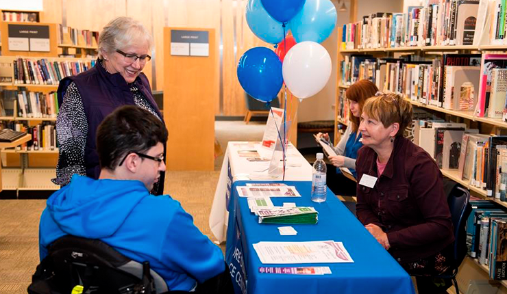 Educator talking to a man in a wheelchair. 