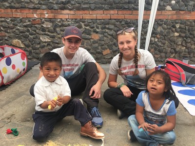 Sebastian sits with three children cross-legged