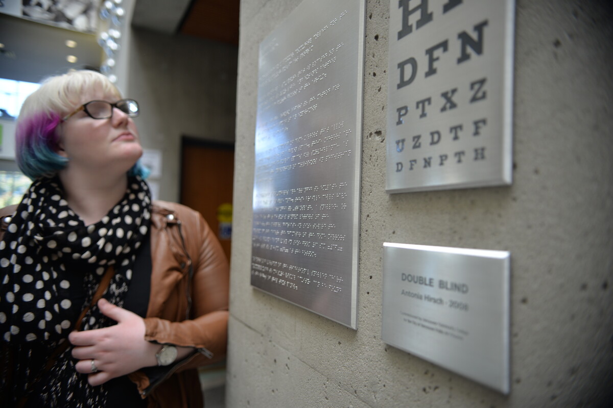 Woman reading braille on a wall