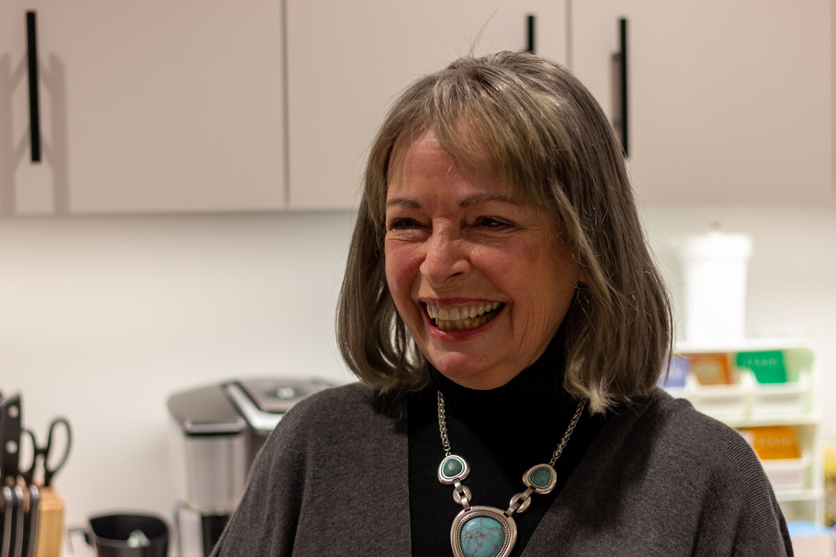An older woman who has shoulder length greyish hair laughing.