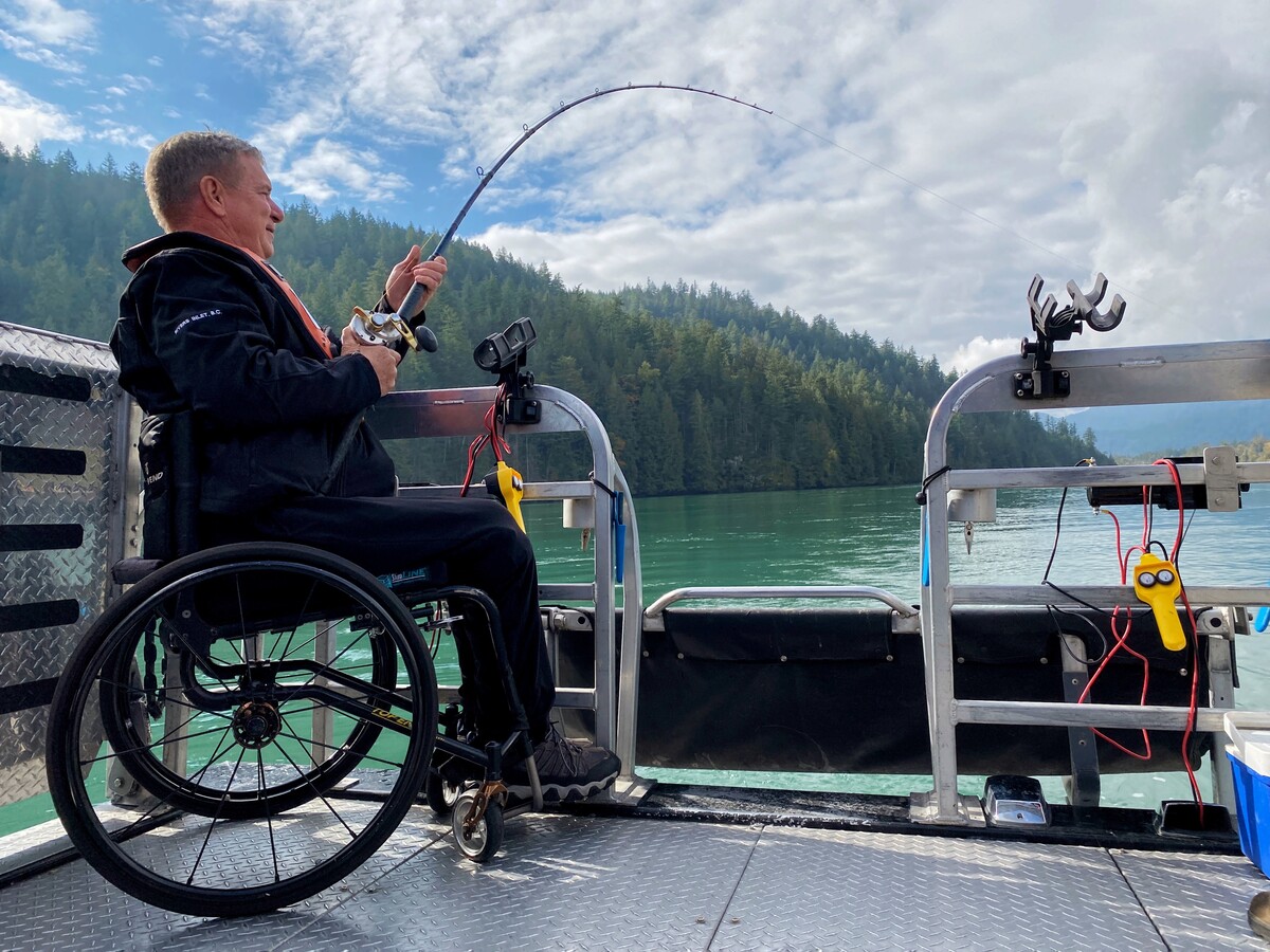 Side profile of Rick Hansen fishing from the back of a boat.