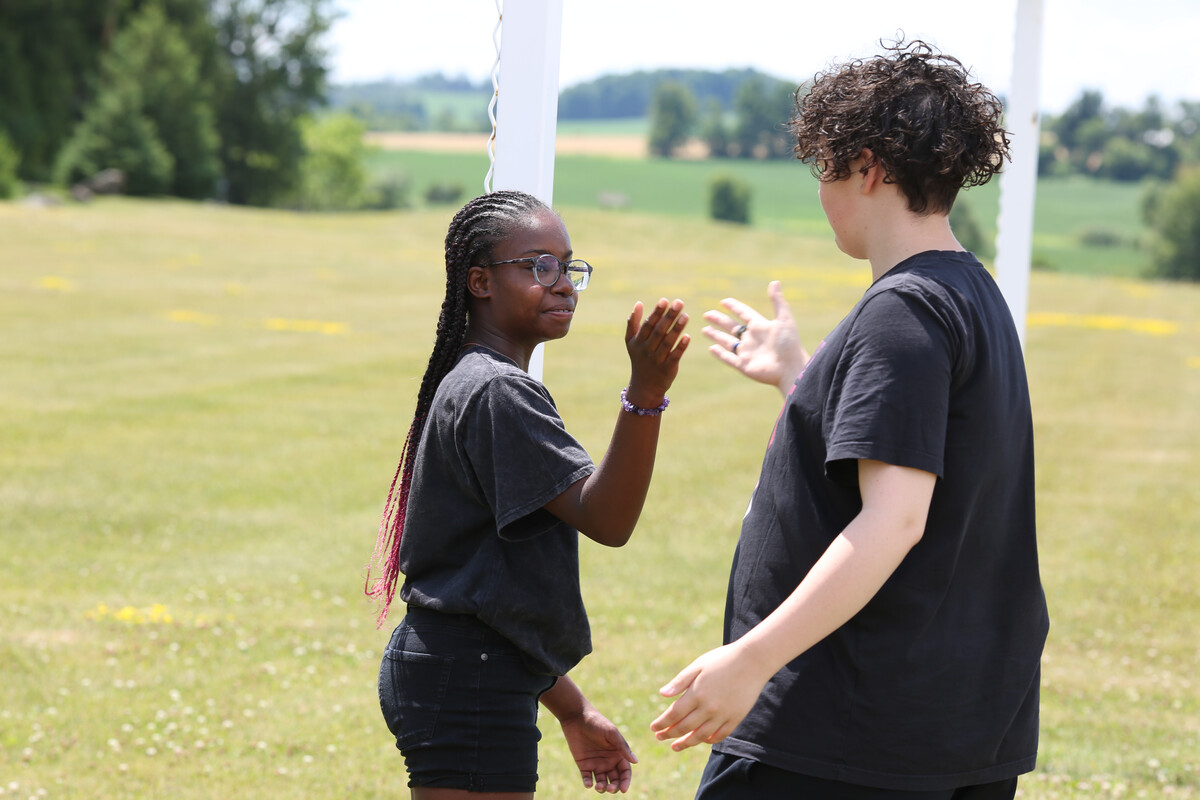 Two young people smiling at each other and bringing their hands together as a gesture of "hello"