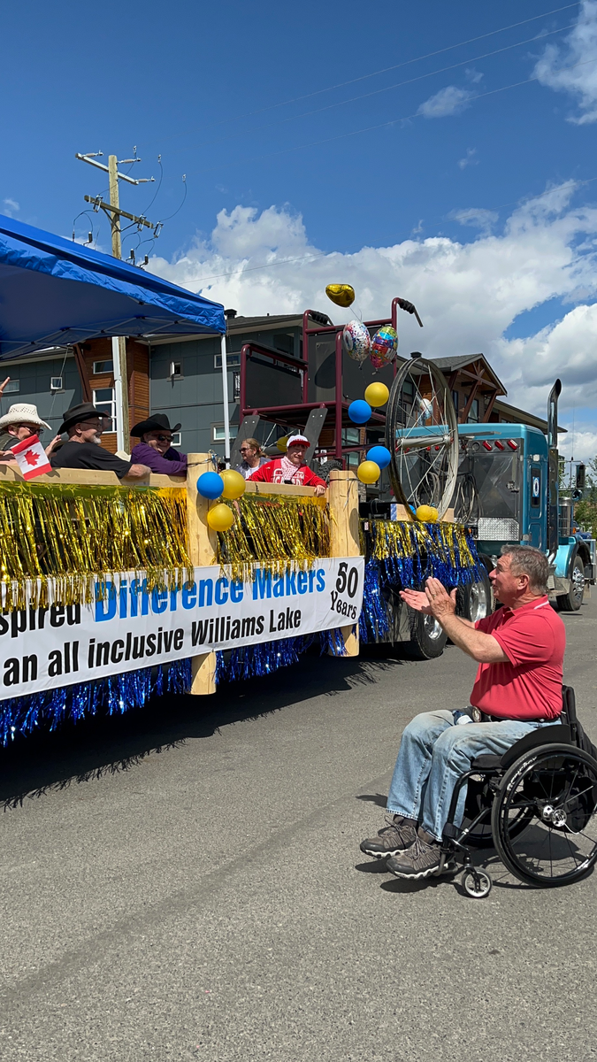 Rick Hansen at the 2023 Williams Lake parade applauding a group of Difference Makers on a float.