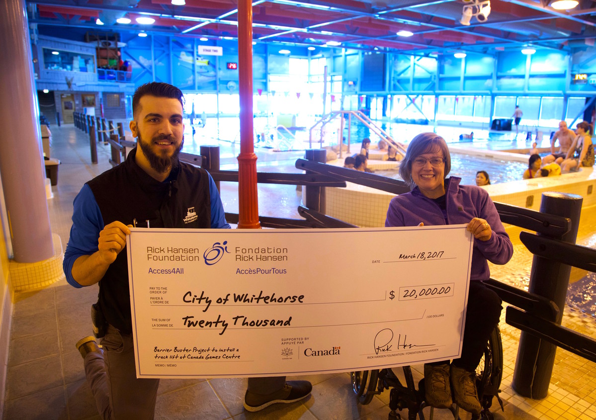 Woman using wheelchair presents cheque to pool