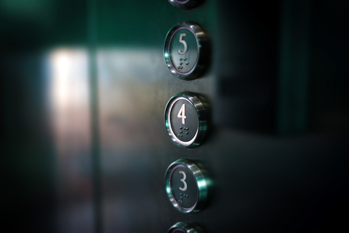 Close-up of elevator buttons. Each button is metallic with raised numbers and Braille