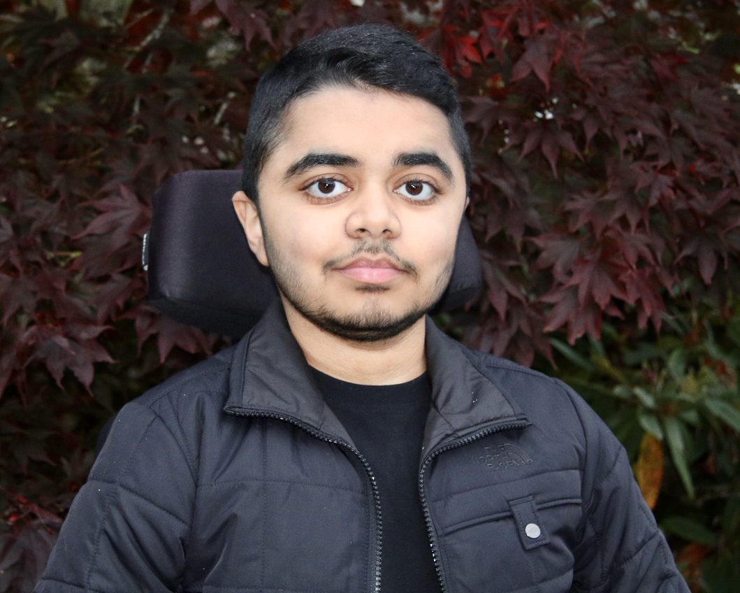 young man with dark hair using a wheelchair outdoors