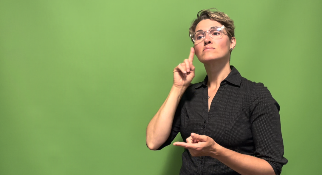 woman with short hair and glasses signs 'believe' in ASL
