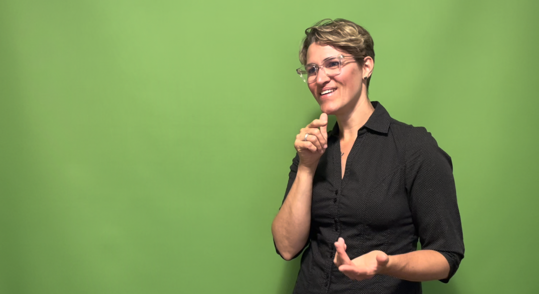 woman with short hair and glasses signs 'who' in ASL