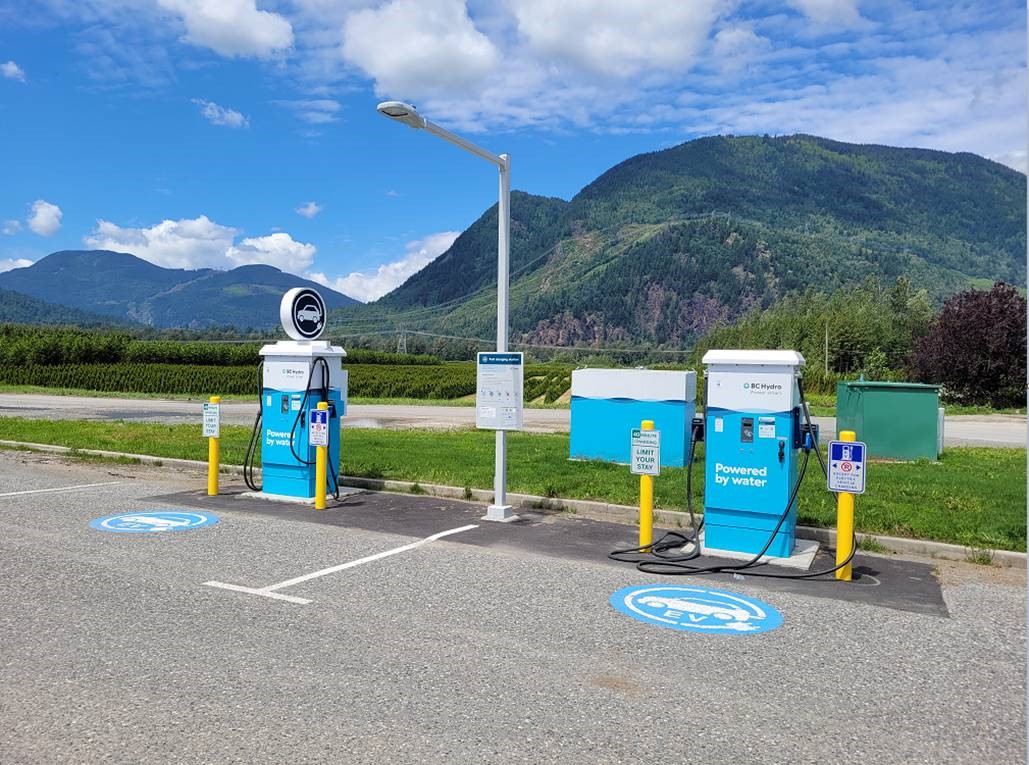 Accessible electric vehicle charging stations in Agassiz, British Columbia. The charging stations are blue and white. There are mountains in the background.