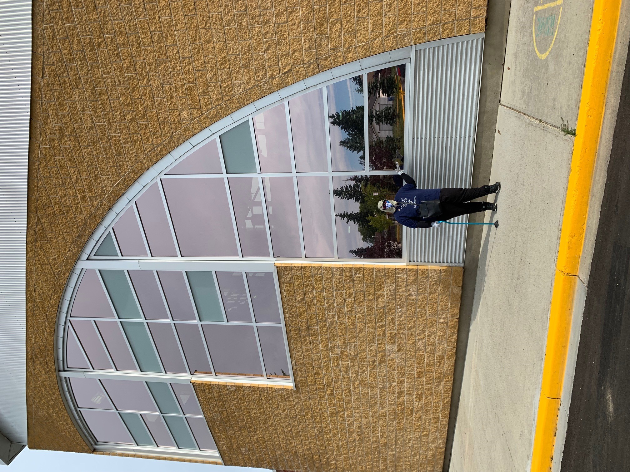 Alexis outside a building, wearing clothing to protect her from UV rays, next to shaded windows