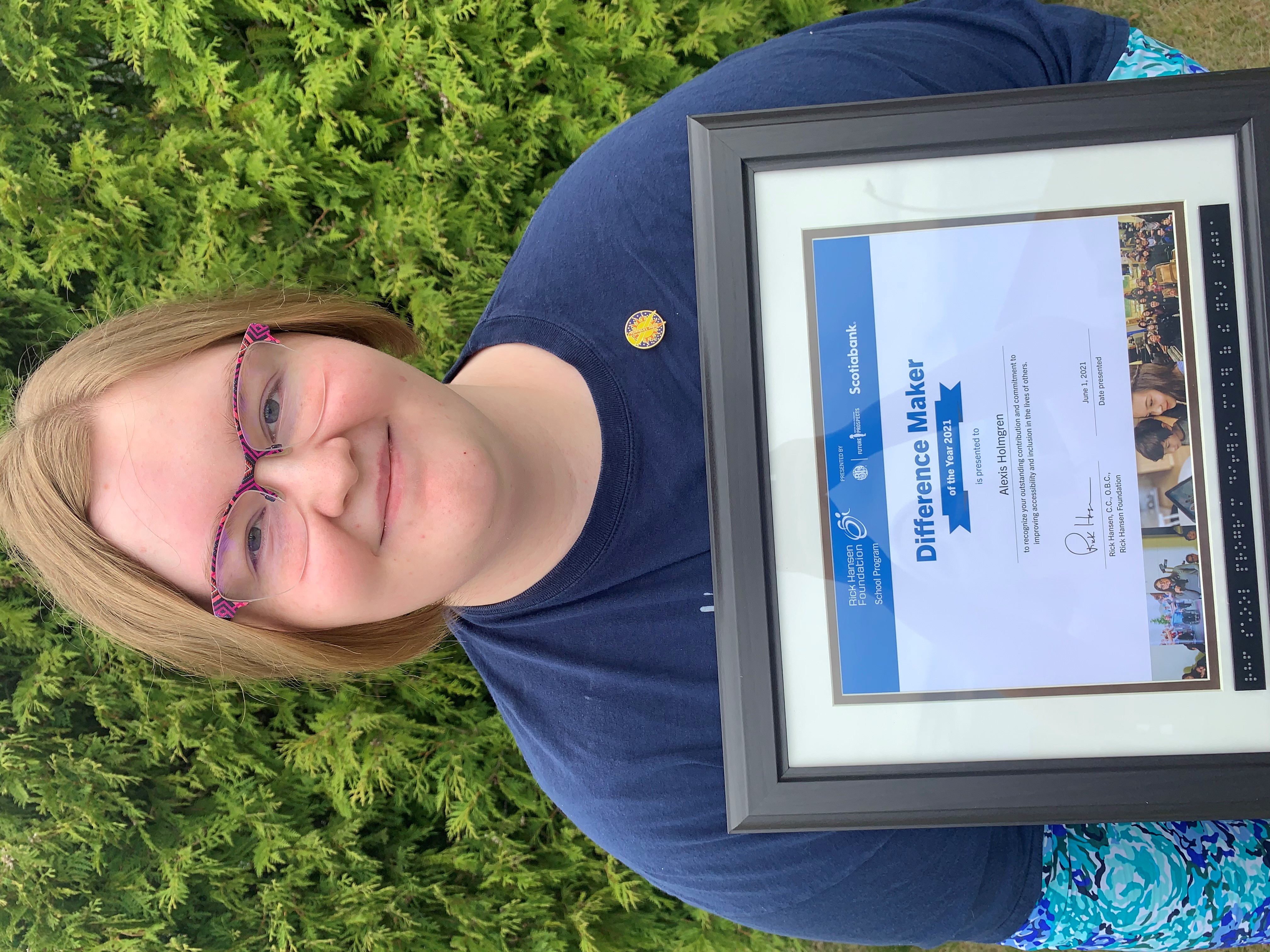 Alexis outside holding her Difference Maker of the Year Certificate