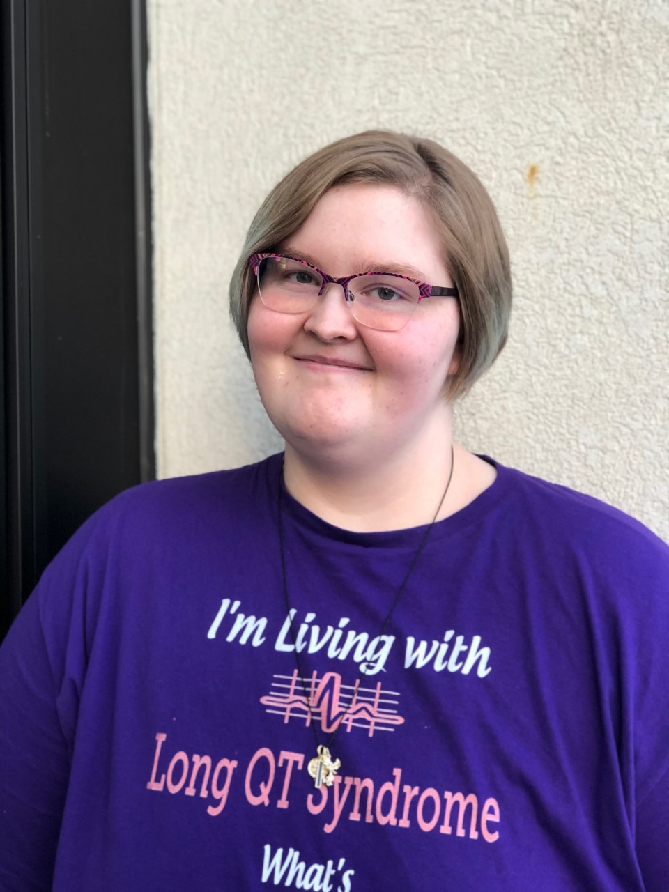 Girl wearing glasses and a purple t shirt, smiling