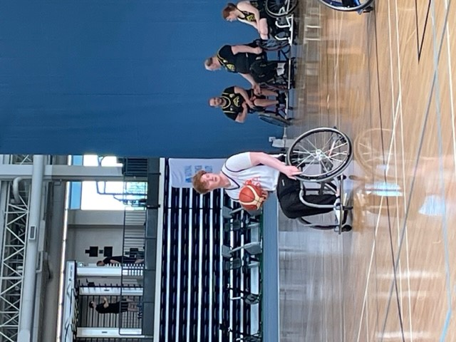 Cameron holding a basketball and sitting on the basketball court - ready for action.