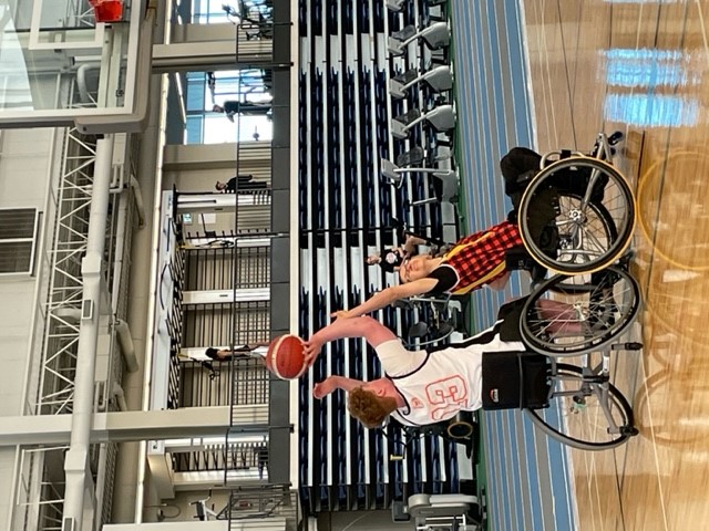 Cameron shooting a basketball on the court. Someone is trying to block his shot.