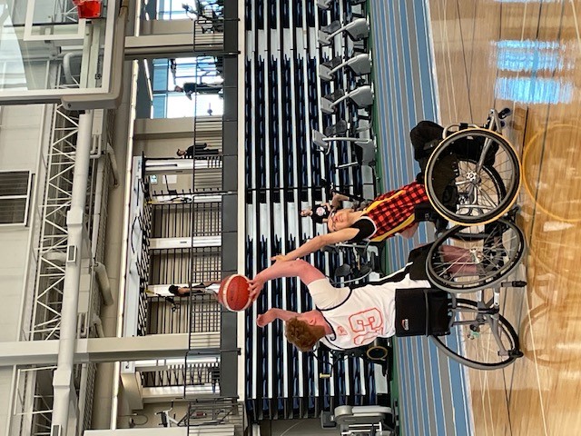 Cameron playing basketball with another wheelchair user. 