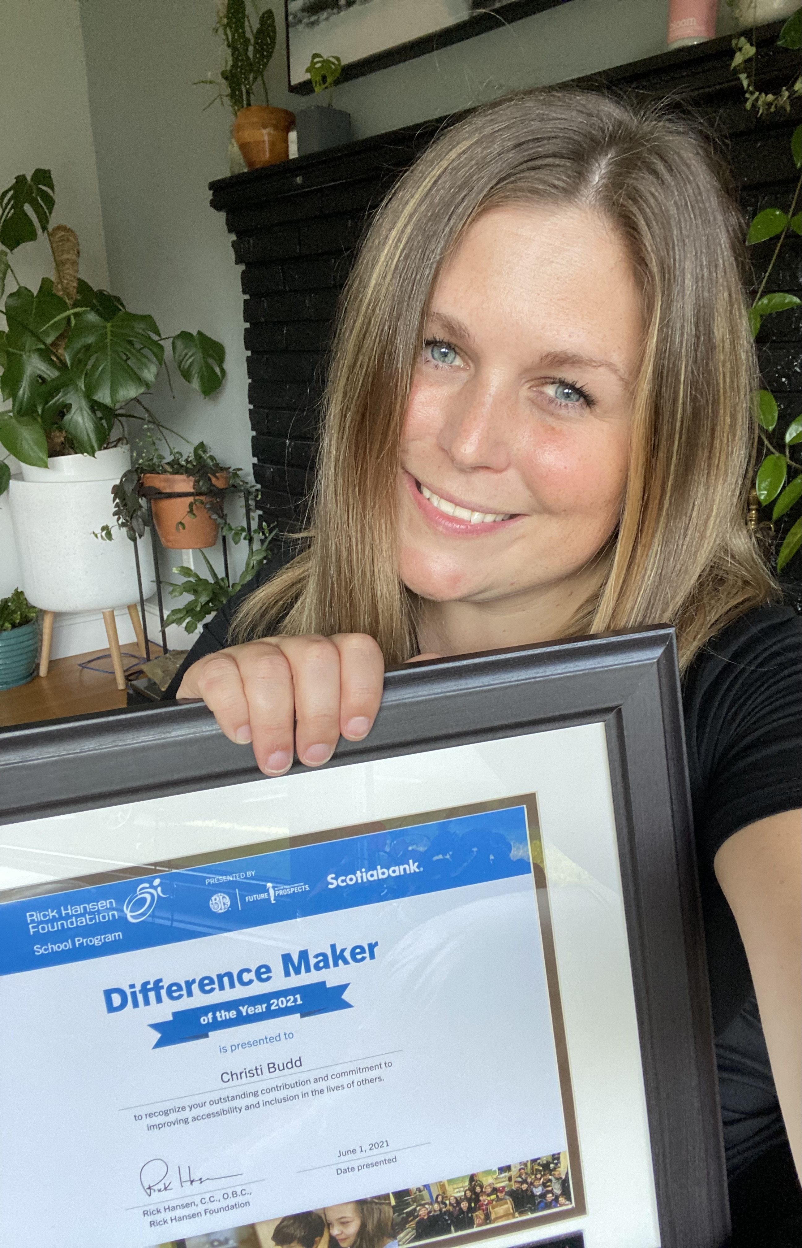 woman with short brown hair holds up a difference maker award certificate