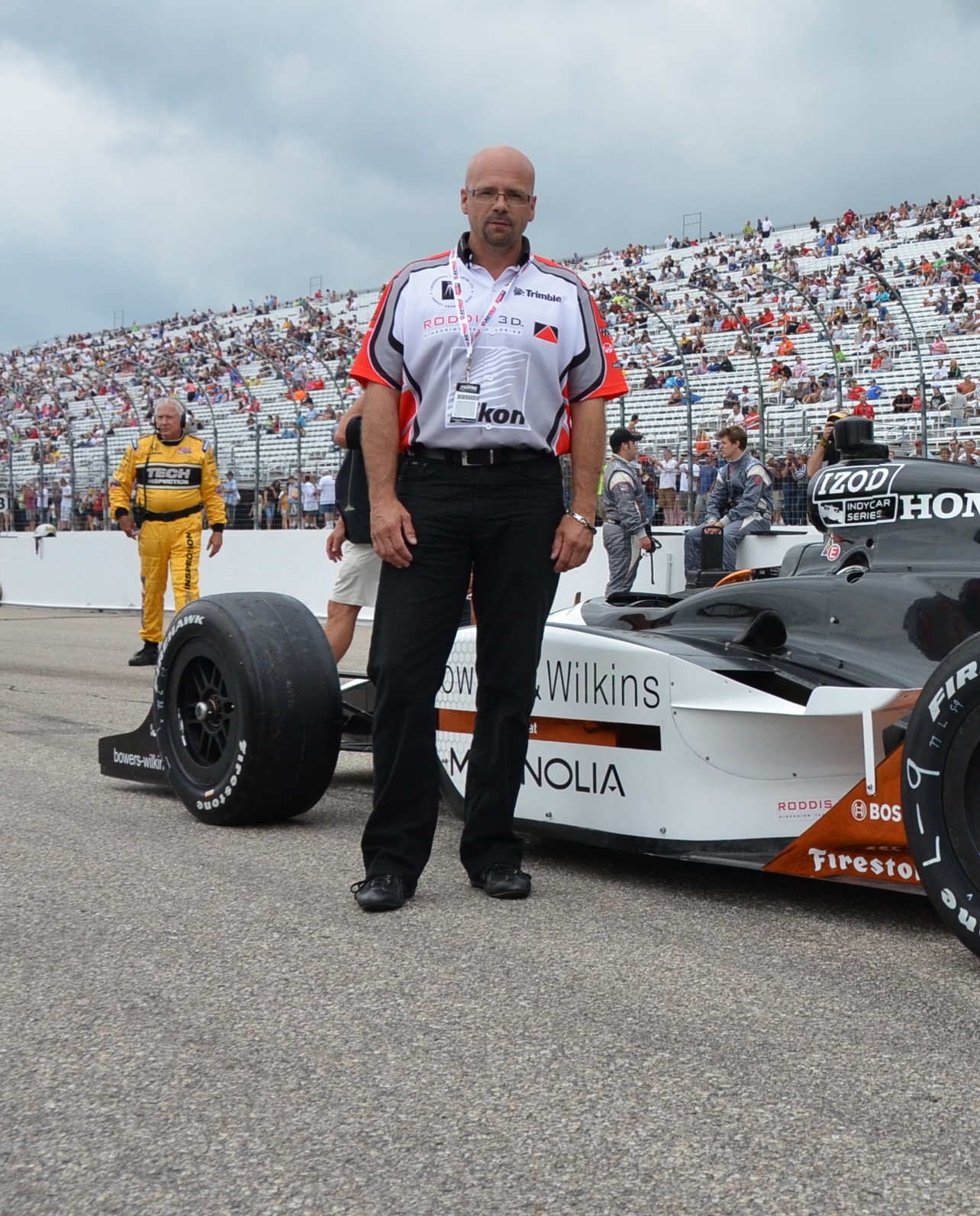 Murray Roddis standing in front of a race car on a track. 