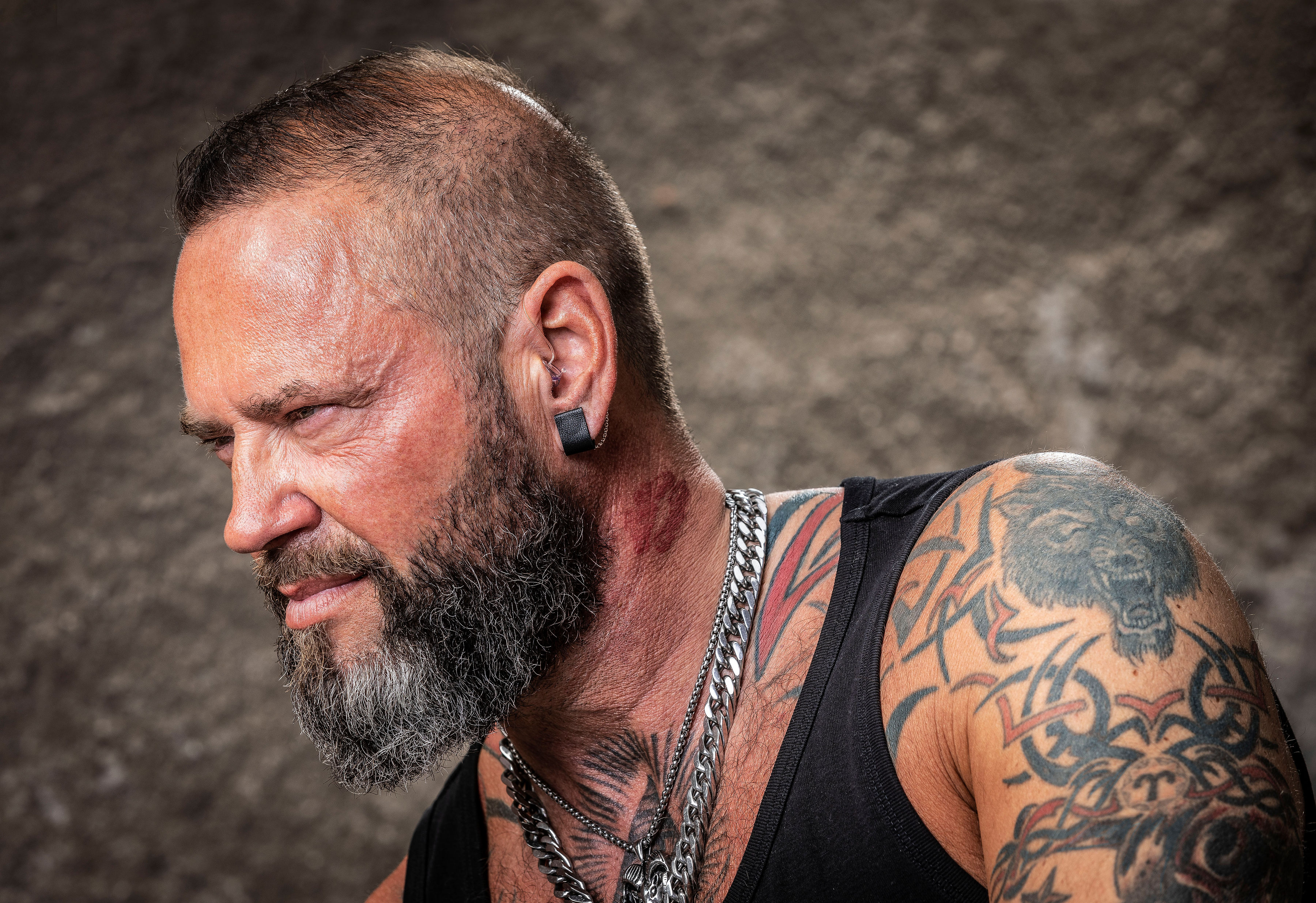 A man models a black stubbed earring attached to his hearing aid.