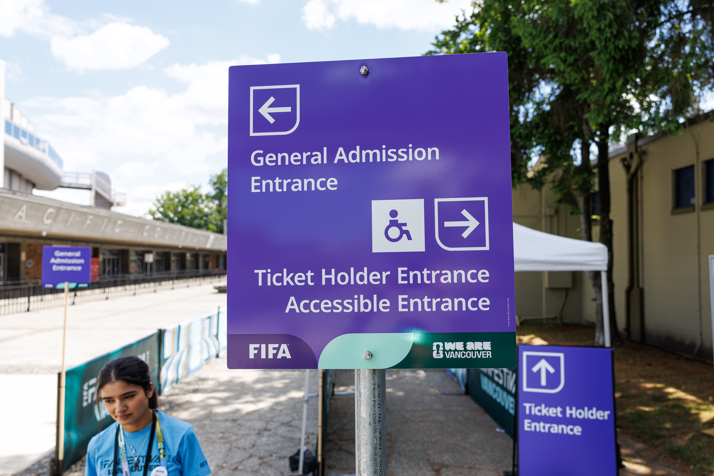 Purple sign directing visitors to the General Admission Entrance and Accessible Entrance, featuring the international accessibility symbol and directional arrows.