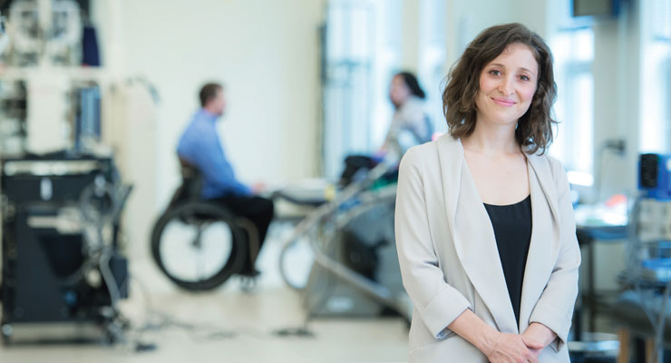 woman smiling, gym with wheelchair users in background