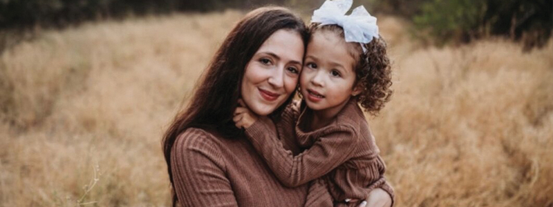 Katie Van Gurp holding her daughter Holland. They are wearing matching brown sweaters.