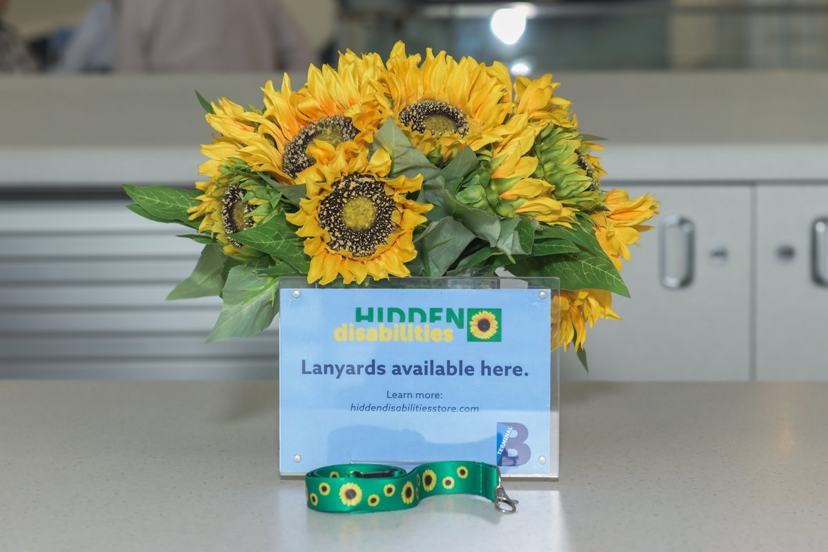 Hidden Disabilities lanyards on desk by sunflowers in vase at LaGuardia airport