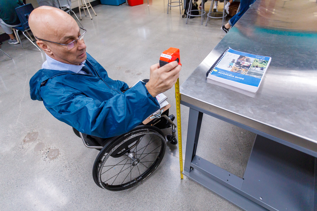 wheelchair user measures counter height 