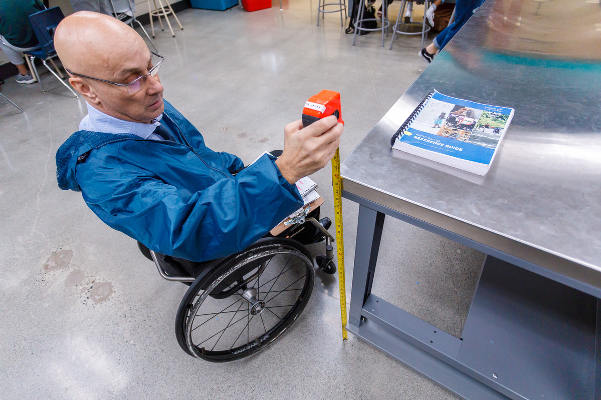 wheelchair user measures counter height