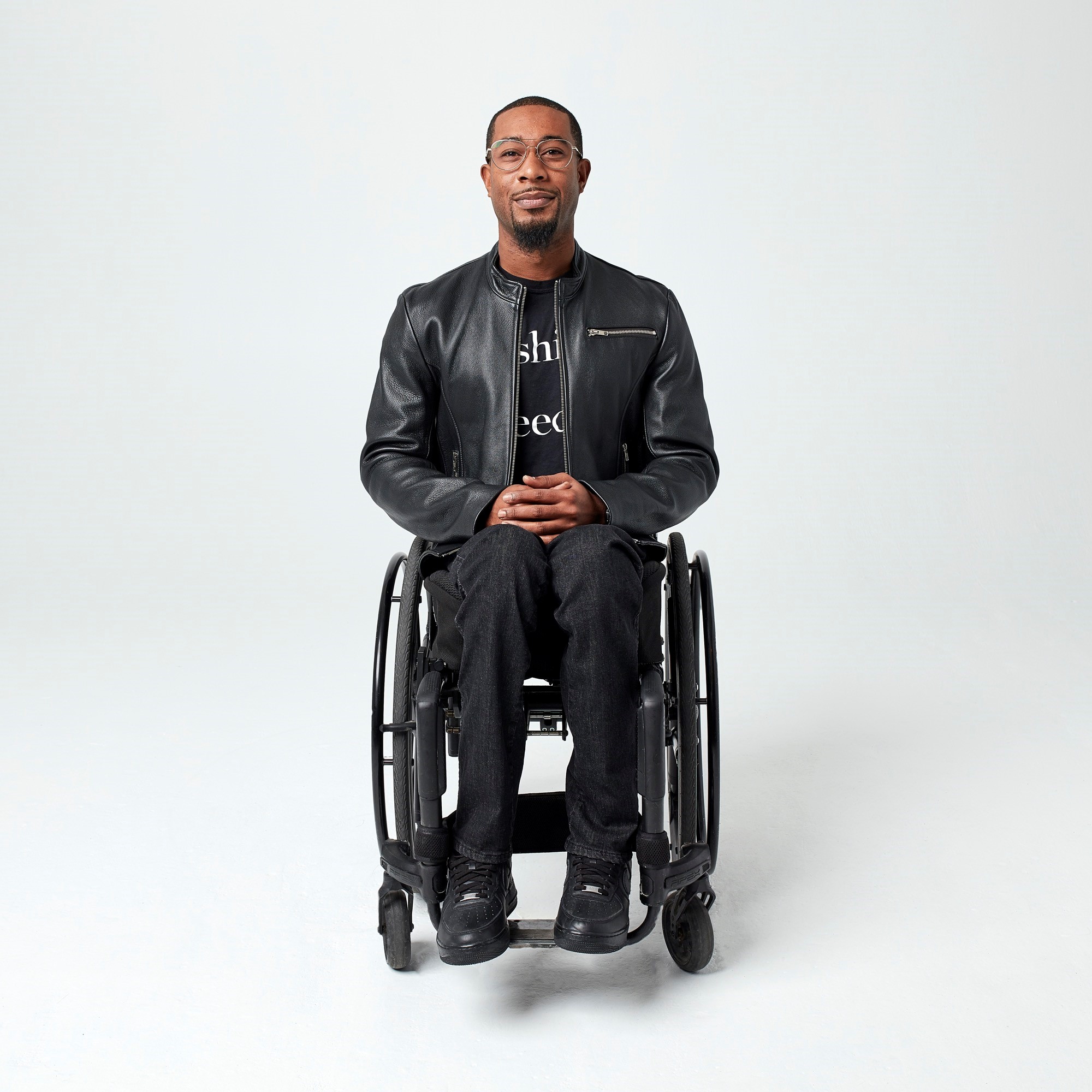 Man in all black clothes, stylish, in a wheelchair with a plain white background