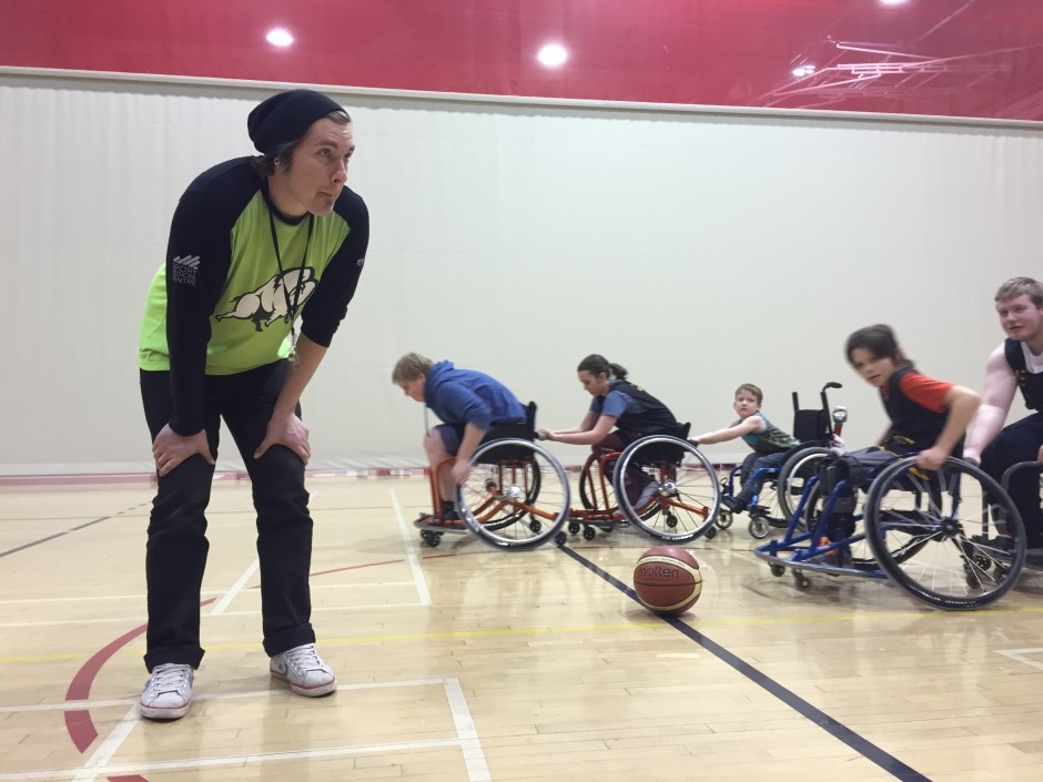 Coach leaning towards young wheelchair athletes in a gymnasium