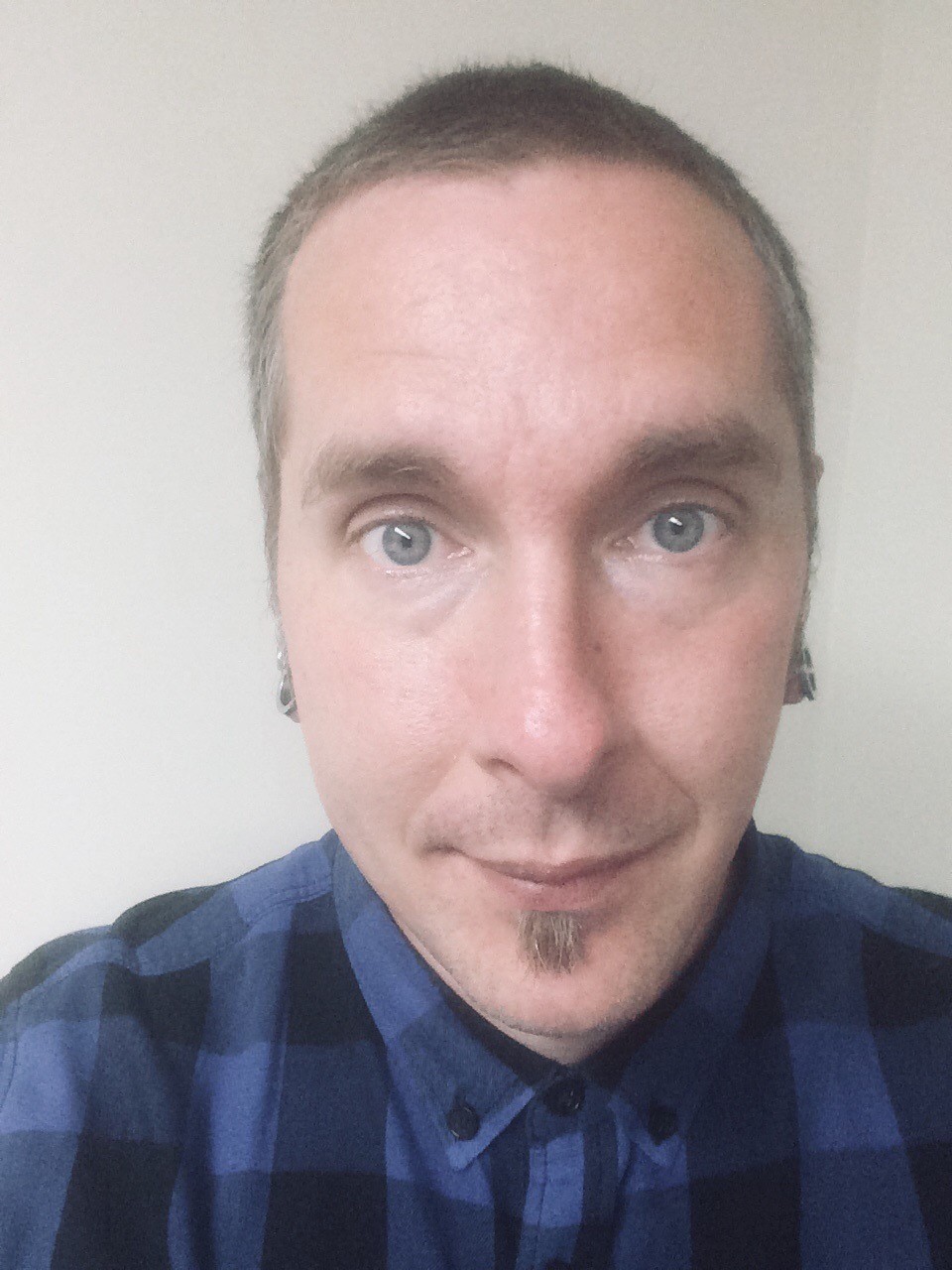Selfie of a light skinned manned with facial hair and a plaid
