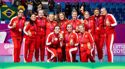 Team Canada sitting volleyball team holding gold medals. They are in red track suits.