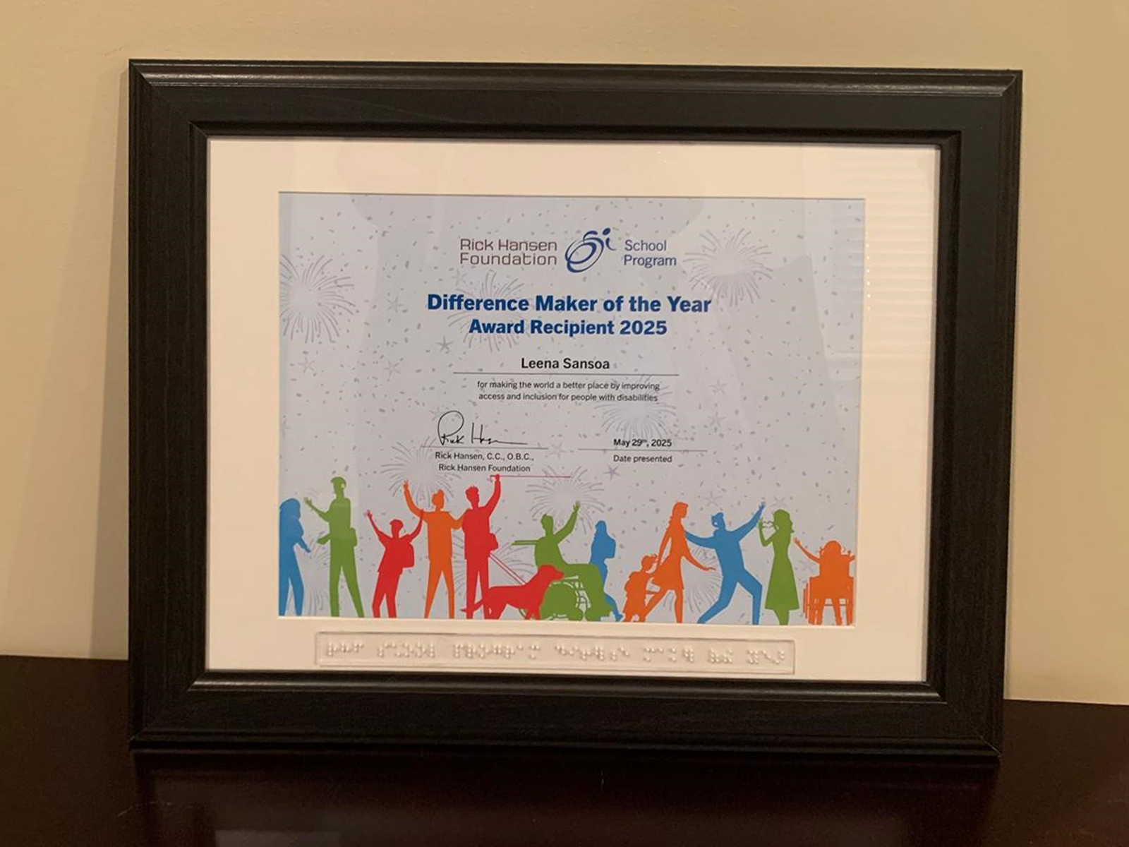 Framed certificate titled "Difference Maker of the Year Award Recipient 2025" with the name Leena Sansoa and braille text below