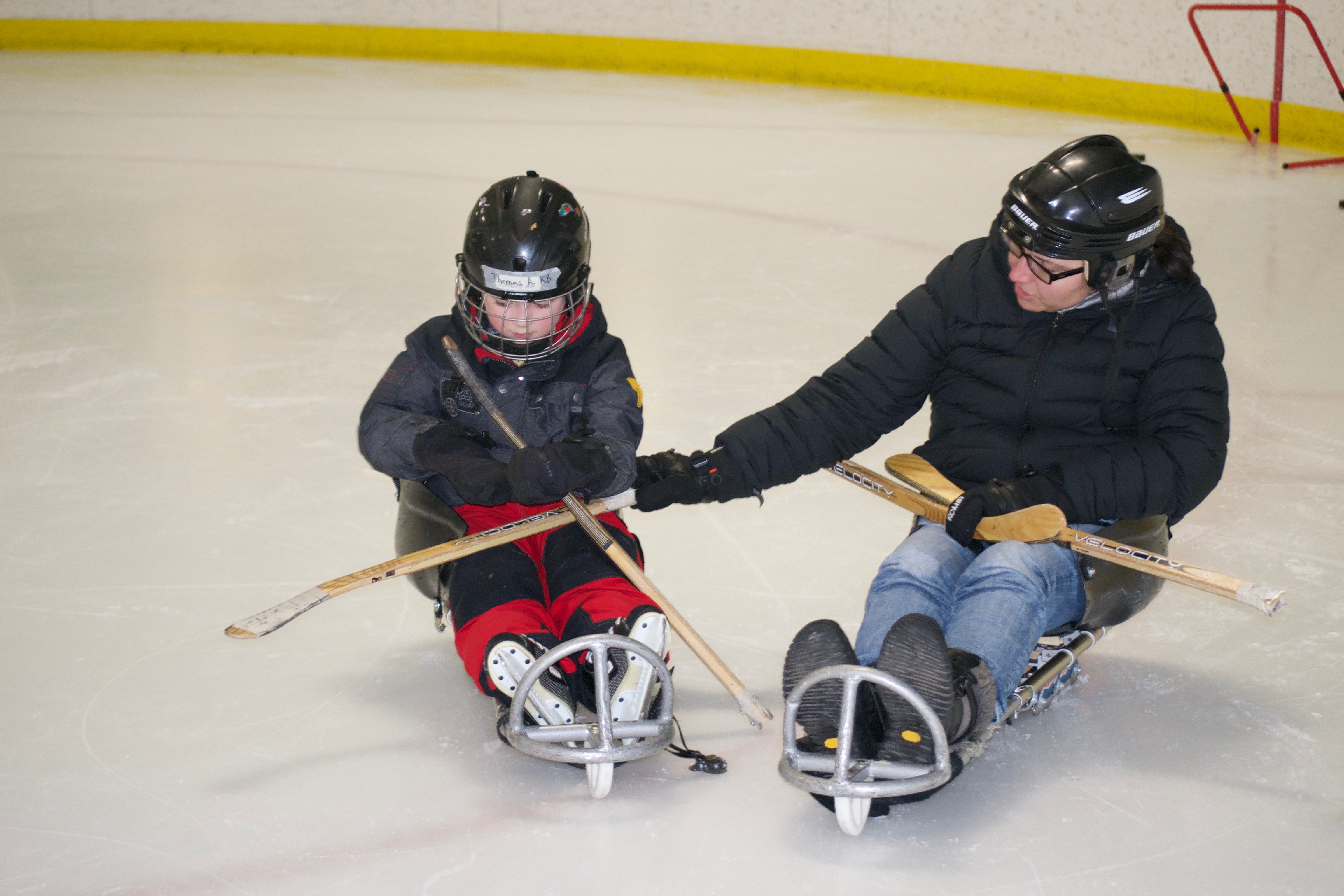 Marjorie and her son Thomas playing hockey together on an ice rink.