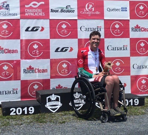 Matt in wheelchair, smiling, in front of red and white checkered backdrop 