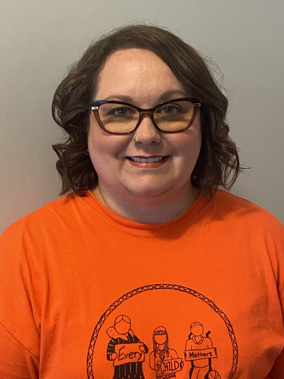 Woman wearing glasses, smiling, orange t shirt