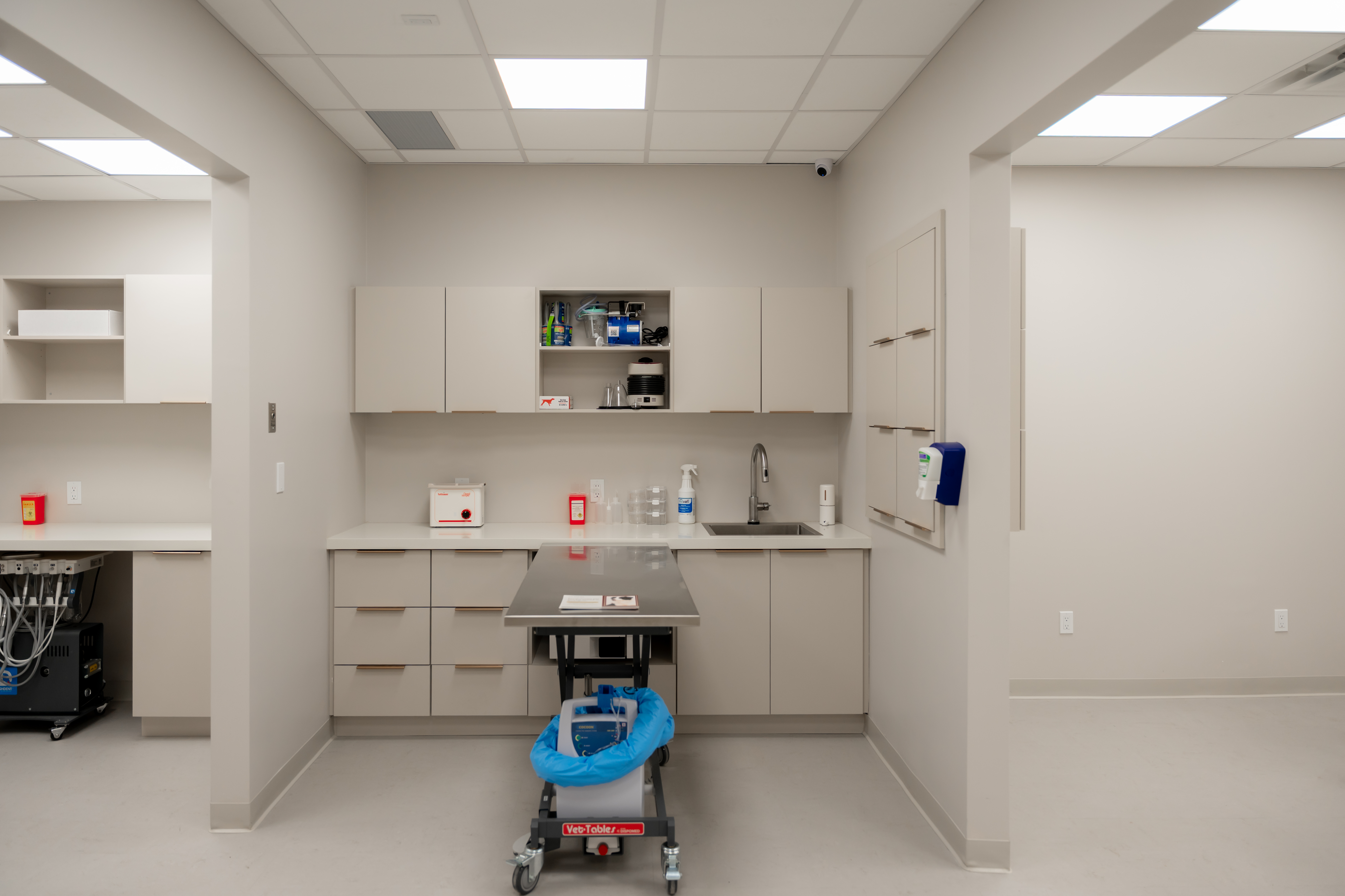 A spacious white room with an adjustable-height table in the center and low cabinets along the side walls