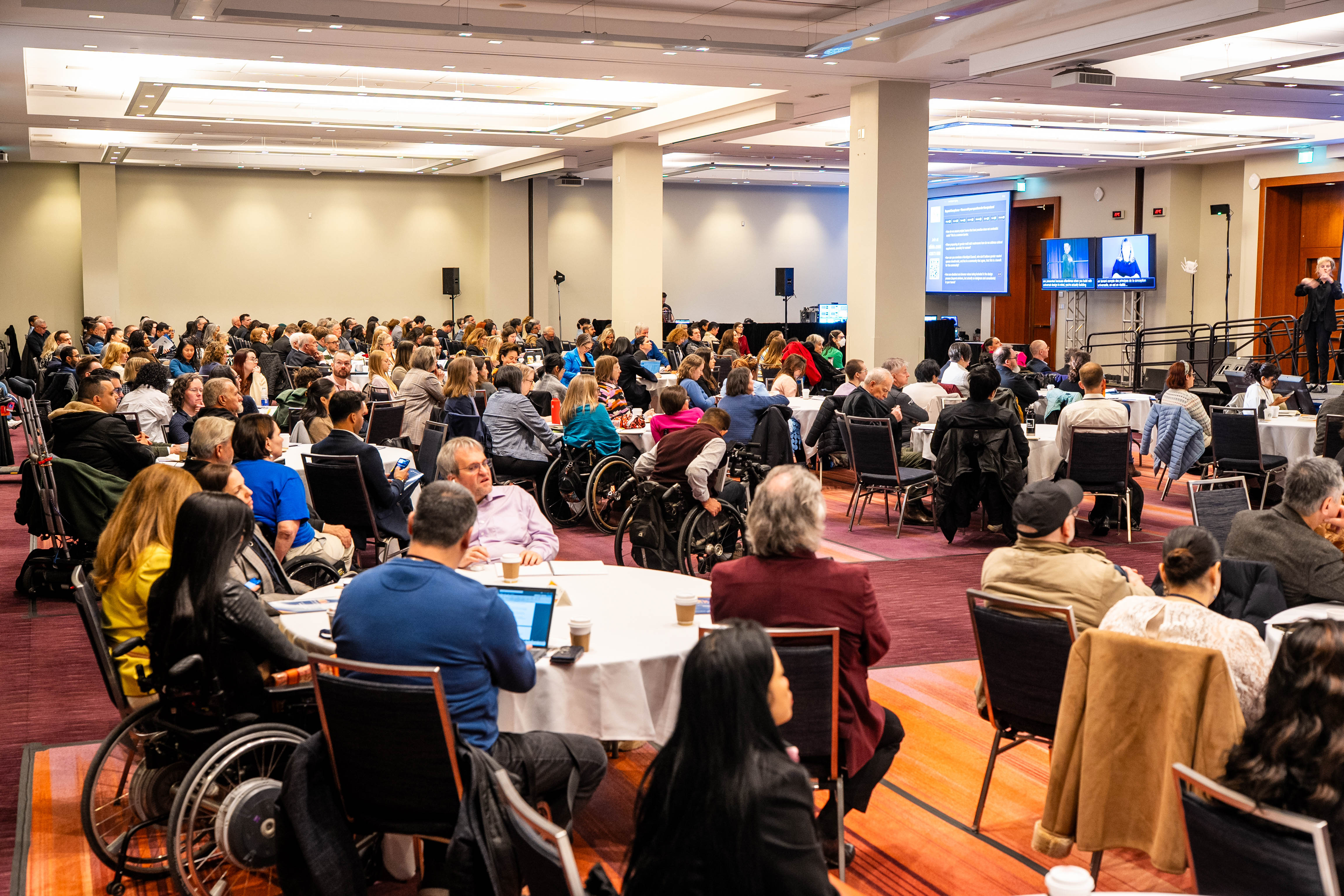 A large audience of attendees watches a presentation at APN 2026